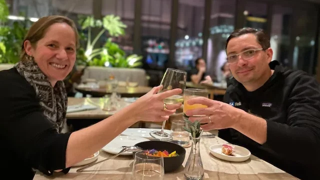 Man and woman cheer glasses at dinner table